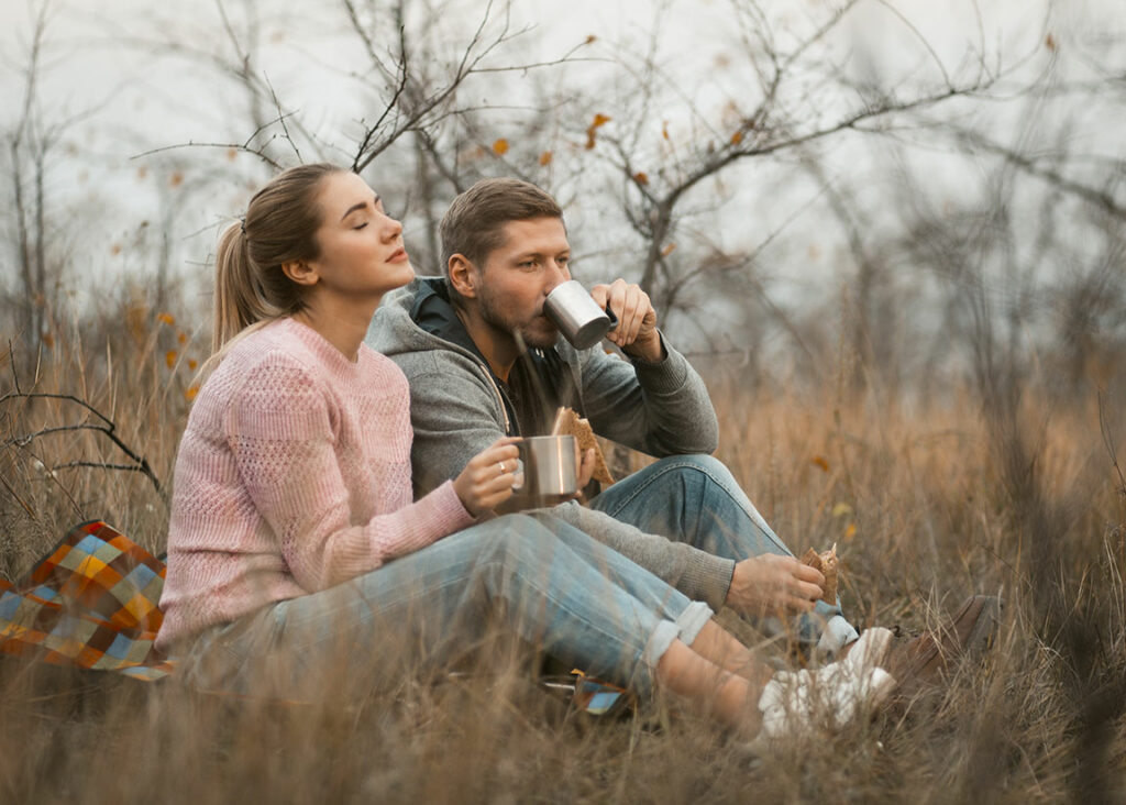 Mann und Frau trinken Tee draußen auf einer herbstlichen Wiese