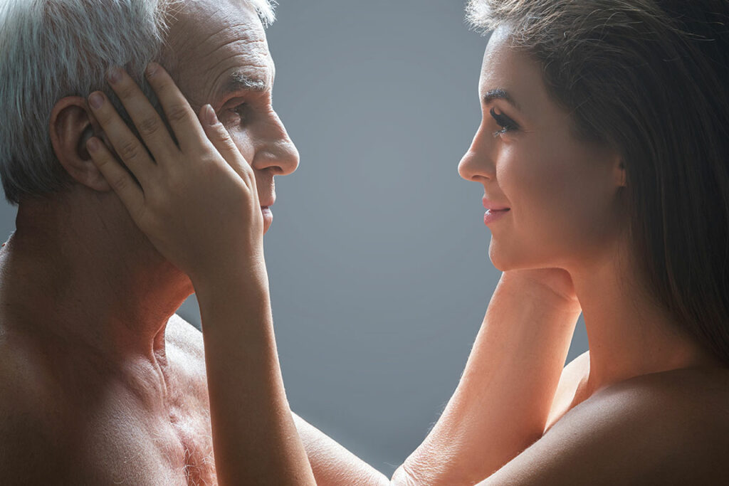 Alter Mann und junge Frau schauen sich gegenseitig an und fassen sich an die Wange