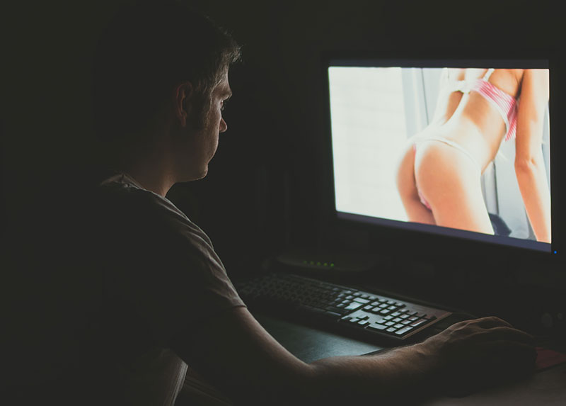 Mann schaut Porno auf seinem Computer im Dunkeln