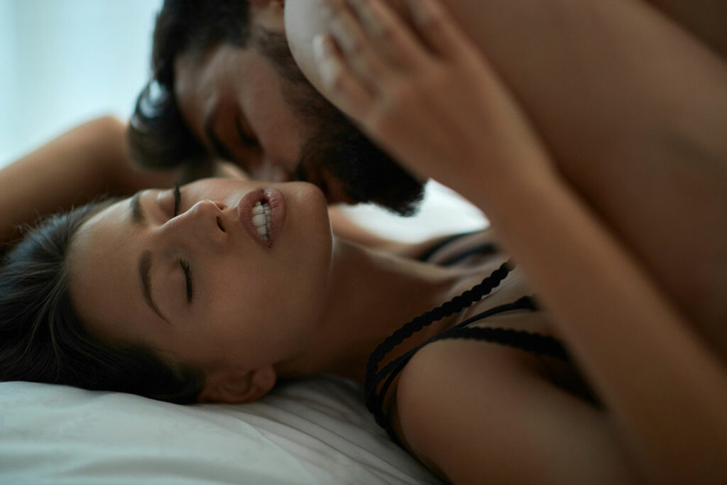 Mann und Frau liegen auf dem Bett und genießen leidenschaftlich