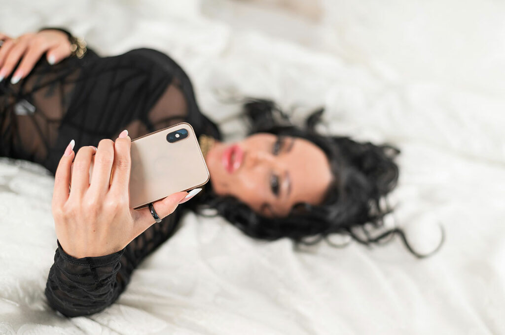 Frau liegt auf dem Bett und macht ein Selfie