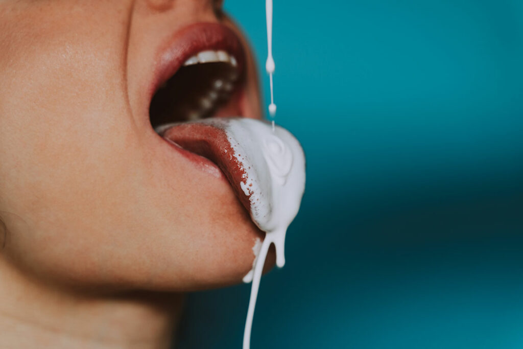 Frau bekommt milchige Flüssigkeit auf ausgestreckte Zunge